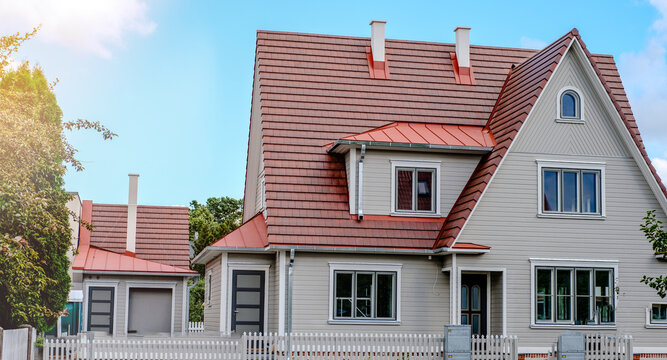 A private house of two floors with triangular roof and an area near the house against a blue sky