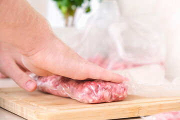 A man makes flat minced pork and beef in bags for storage in the freezer.