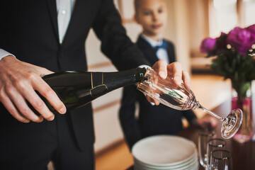 The groom pours champagne into a glass