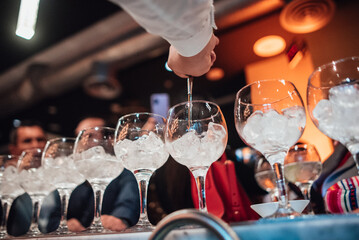 Bartender serves liquor in a line of glasses. Bartender serves liquor in a glass. Copy space