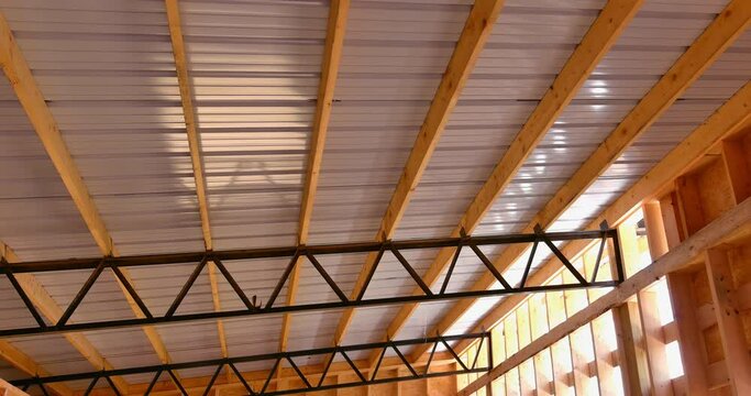 Roofing metal panels cover the roof of a metal frame warehouse in construction site