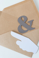 paper ampersand and pictographic glyph of a pointing hand on a plain brown envelope