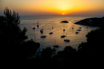 Naklejka premium Several pleasure boats anchored in a cove on the island of Ibiza to watch the sunset.
