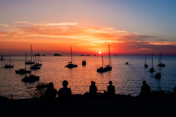 Young people admire a beautiful sunset over the horizon of the Mediterranean Sea.