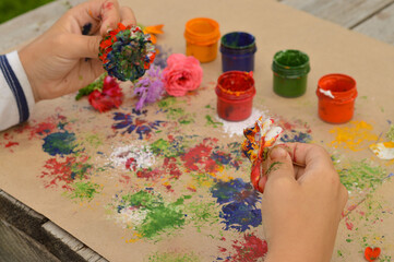 Close-up of children's hands that create a drawing using a flower by poking. What to do with children in kindergarten or school camp in the summer.