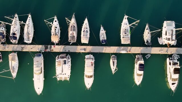 Ascending top down aerial view of yachts moored to pier. Luxury boats parked in marina