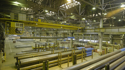 Yellow Indoor Crane. Work hanging of a crane at the plant for the production of pipes