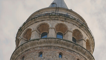 Bottom view of Galata Tower. Action. Ancient stone tower on background of blue sky. Historical...