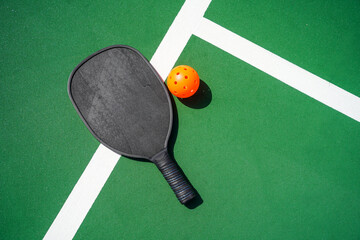 Pickleball paddle and pickle ball on court. - obrazy, fototapety, plakaty