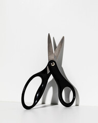Single kids black handled scissors leaning on white background with shadow