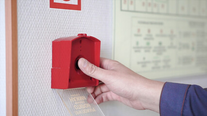 The hand of man is pushing fire alarm on the wall. Clip. Hand of man pushing fire alarm switch on the white wall as background for emergency case at the new factory building