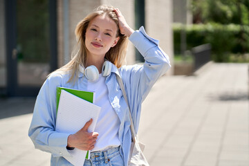 Pretty smiling girl university student holding notebooks looking at camera posing for outdoor portrait. College study programs, academic education ads, admission and scholarship.