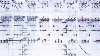 Fototapeta na wymiar Rows of electric poles. Action. Top view of electrical substation with rows of transformers in winter. Powerful electrical substation with new equipment in winter. Electric power industry