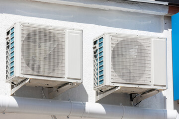 two units of outdoor air conditioners for heat dissipation are hung on the wall outside the building