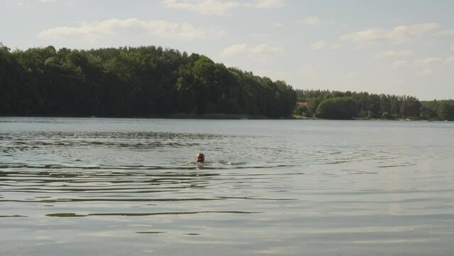 Shirtless Man Swims On The Lake Of Jezioro Glebokie In Poland. Static Shot