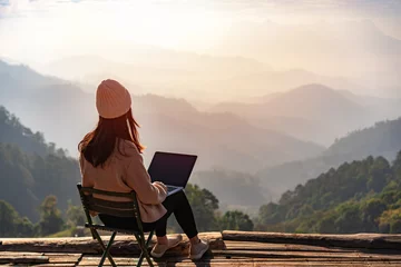 Foto op Plexiglas Zalmroze Jonge vrouwelijke freelancer-reiziger die online werkt met laptop en geniet van het prachtige natuurlandschap met uitzicht op de bergen bij zonsopgang