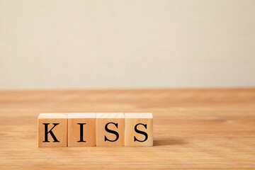 KISSの文字。キス。簡略化。Keep It Simple, Stupid。4つの木製ブロックに書かれている。白い背景。