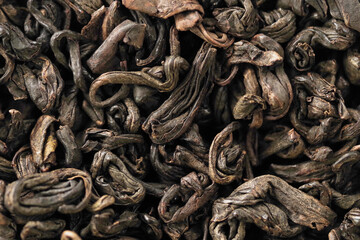 Premium black loose leaf tea as a background. Texture of dry black tea leaves. Extreme macro mode
