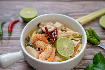 Close up of Hot and Sour Seafood Soup in a white bowl on wood table. Thai food made. (Tom Yum...