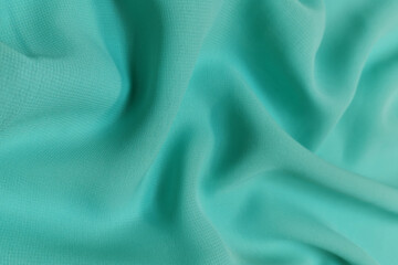 Green chiffon fabric crumpled or wavy fabric texture background. Abstract linen cloth soft waves. Silk yarn. Smooth elegant luxury cloth texture. Concept for banner or advertisement.