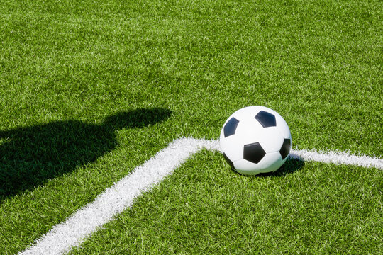 Soccer football sport background. Soccer ball and shadow of player on artificial turf soccer field in sunny day outdoors