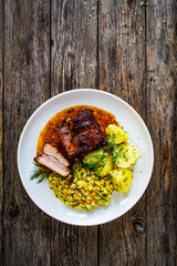 Tasty roast ribs with boiled potatoes and coleslaw on wooden table
