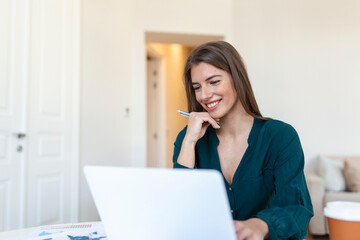 Business woman analyzing data using computer while spending time in the office. Beautiful young grinning professional woman in office. Graphs and charts