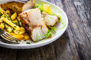 Fish dish - fried halibut with French fries and lemon on wooden table
