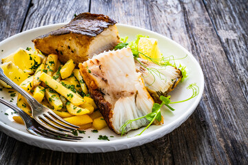 Fish dish - fried halibut with French fries and lemon on wooden table
