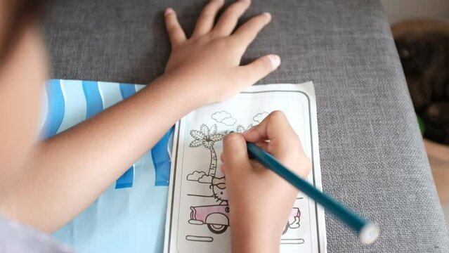 Girl's hands are coloring pictures on paper at home