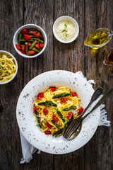 Pasta with asparagus, parmesan and tomatoes on wooden table
