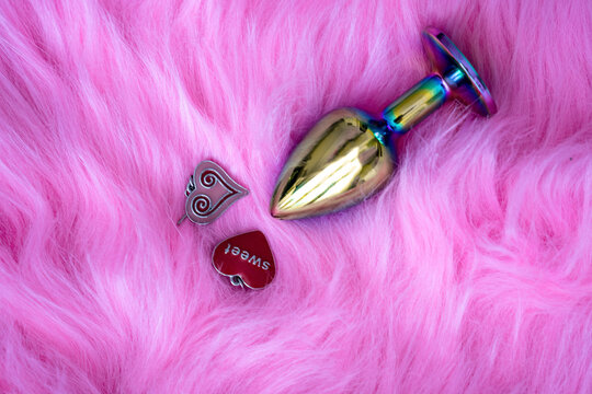 anal butt plug sex toy on fur pink background, sex shop advertisement, next to heart