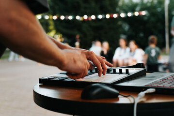 Musician beatmaker playing on an electronic drum machine controller at street music festival,...
