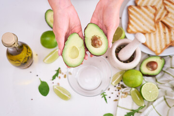 Making avocado toast - Woman hold fresh ripe halved avocado
