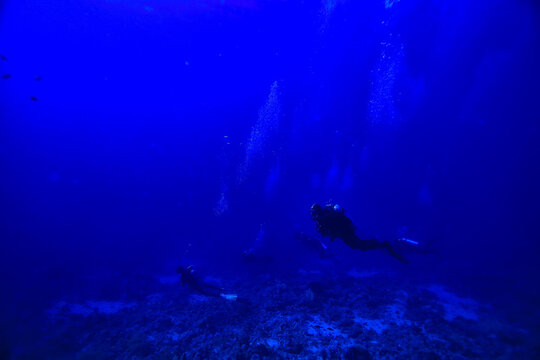 divers underwater at depth in the blue sea background