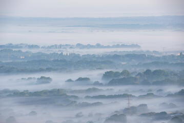 Glorious landscape image of layers of mist rolling over South Downs National Park English countryside during misty Summer sunrise