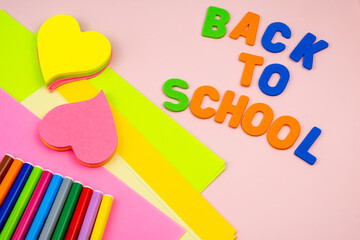 Back to school letters, with school supplies on top of a pink table.