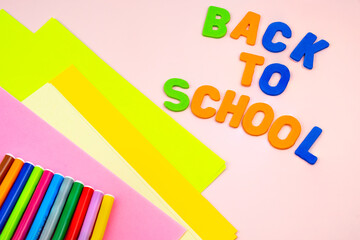 Back to school letters, with school supplies on top of a pink table.