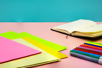 Back to school, with school supplies on top of a pink table with a blue background.