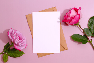 Creative concept, greeting card template. Styled feminine flat lay on pale peach background, top view. Minimal woman's desktop with blank page mock up, envelope, rose flowers.