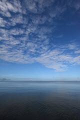 Fototapeta na wymiar 風がない波の穏やかな湾内の海と澄み切った青空、夏の朝の風景