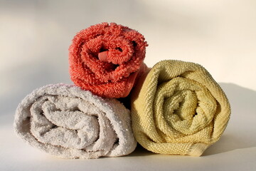  twisted towels lie on top of each other, sunny morning light, white background
