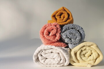  twisted towels lie on top of each other, sunny morning light, white background
