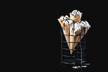 Cones of homemade vanilla ice cream with chocolate on a dark background.Copy space