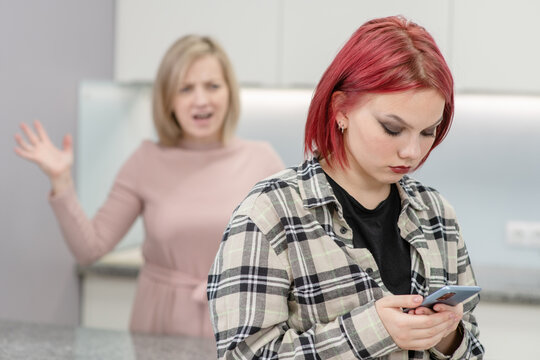 Angry mother scolds her teenage daughter, girl uses smartphone and ignores her mom. Family relationships