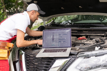 Mechanic man close up using laptop computer examining tuning fixing repairing car engine automobile...