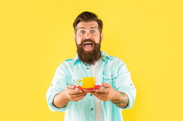 surprised bearded man drink morning coffee on yellow background, cappuccino