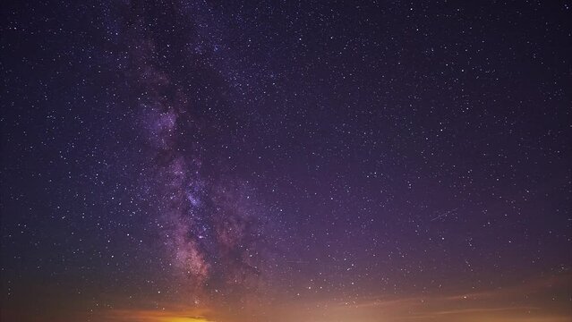 The core of the milkyway in the night sky,the silhouette of the hills and glowing city in the valley