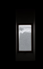 Roof window covered with snow. The snow on the glass blocks the light in a dark room.
