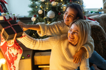 Mother and daughter in front of Christmas tree, opening presents